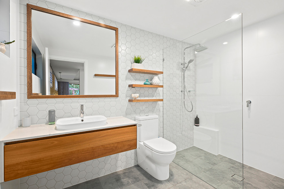 Design ideas for a medium sized contemporary family bathroom in Other with flat-panel cabinets, medium wood cabinets, a walk-in shower, a one-piece toilet, white tiles, ceramic tiles, white walls, ceramic flooring, a console sink, solid surface worktops, grey floors, an open shower, white worktops, a single sink and a floating vanity unit.