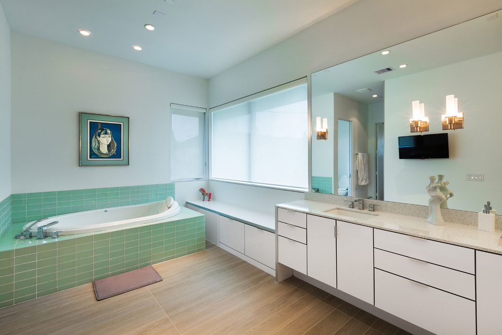 Bild på ett funkis badrum, med ett undermonterad handfat, släta luckor, vita skåp, ett platsbyggt badkar och grön kakel