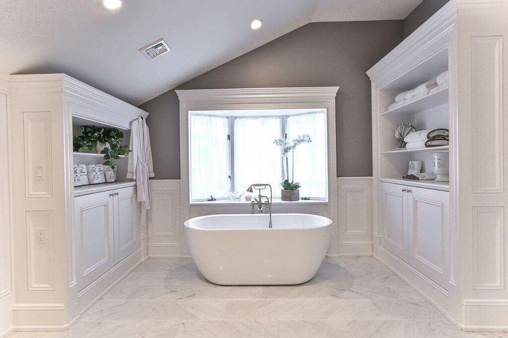 Идея дизайна: большая главная ванная комната в стиле неоклассика (современная классика) с плоскими фасадами, белыми фасадами, угловым душем, серыми стенами, мраморным полом, столешницей из гранита, белым полом, душем с раздвижными дверями и отдельно стоящей ванной