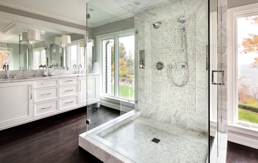 Exemple d'une salle de bain principale et grise et blanche chic avec un placard avec porte à panneau encastré, des portes de placard blanches, une douche double, un mur gris, parquet foncé, un carrelage blanc et une fenêtre.