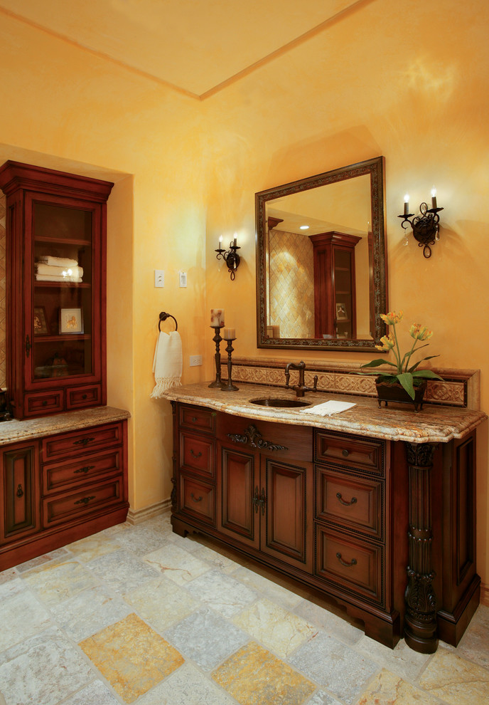 Immagine di una stanza da bagno padronale mediterranea con lavabo sottopiano, consolle stile comò, ante in legno scuro, top in granito, vasca freestanding, doccia alcova e pareti gialle