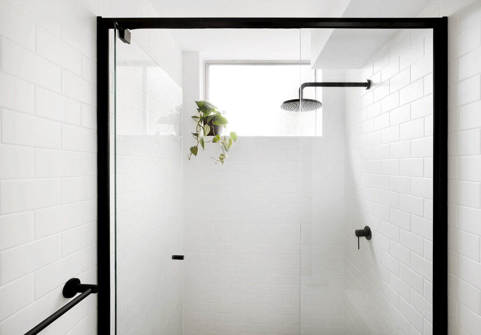 Inredning av ett skandinaviskt litet badrum, med luckor med lamellpanel, vita skåp, en kantlös dusch, vit kakel, tunnelbanekakel, klinkergolv i keramik, laminatbänkskiva, grått golv och dusch med gångjärnsdörr