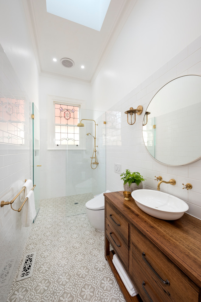 Idéer för att renovera ett minimalistiskt brun brunt badrum, med skåp i mellenmörkt trä, en kantlös dusch, en toalettstol med hel cisternkåpa, vit kakel, vita väggar, ett fristående handfat, träbänkskiva, beiget golv, med dusch som är öppen och släta luckor