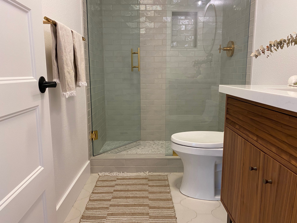 Foto på ett mellanstort minimalistiskt vit badrum med dusch, med släta luckor, skåp i mellenmörkt trä, en dusch i en alkov, en toalettstol med hel cisternkåpa, grå kakel, keramikplattor, vita väggar, klinkergolv i keramik, ett undermonterad handfat, bänkskiva i kvartsit, grått golv och dusch med gångjärnsdörr