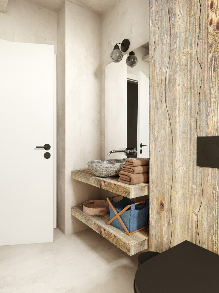 Inredning av ett nordiskt litet badrum för barn, med en kantlös dusch, en vägghängd toalettstol, flerfärgade väggar, betonggolv, ett konsol handfat, skåp i mellenmörkt trä, ett badkar i en alkov, beige kakel, stenkakel, träbänkskiva och öppna hyllor