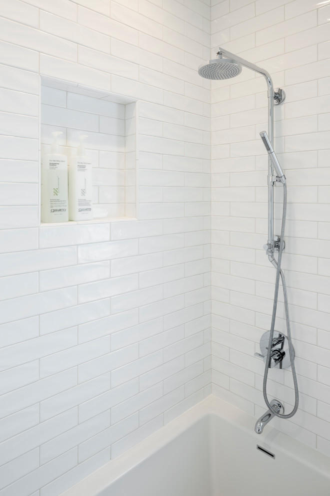 Minimalistisk inredning av ett litet en-suite badrum, med släta luckor, skåp i ljust trä, ett badkar i en alkov, en dusch/badkar-kombination, en toalettstol med hel cisternkåpa, vit kakel, keramikplattor, vita väggar, marmorgolv, ett undermonterad handfat, bänkskiva i kvarts, vitt golv och dusch med gångjärnsdörr