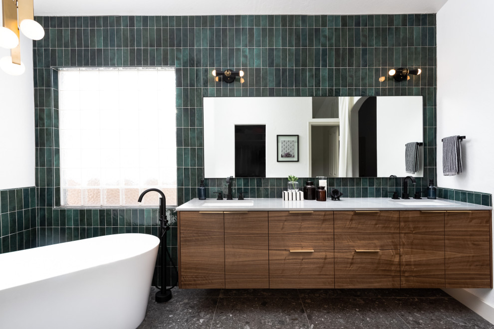 Пример оригинального дизайна: ванная комната в скандинавском стиле с плоскими фасадами, фасадами цвета дерева среднего тона, отдельно стоящей ванной, зеленой плиткой, белыми стенами, врезной раковиной, серым полом, белой столешницей, тумбой под две раковины и подвесной тумбой