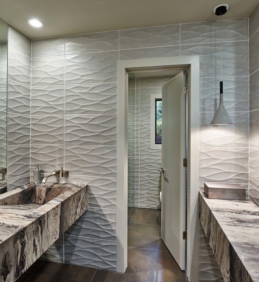 Diseño de cuarto de baño principal actual de tamaño medio con lavabo integrado, baldosas y/o azulejos grises, paredes grises y suelo de travertino