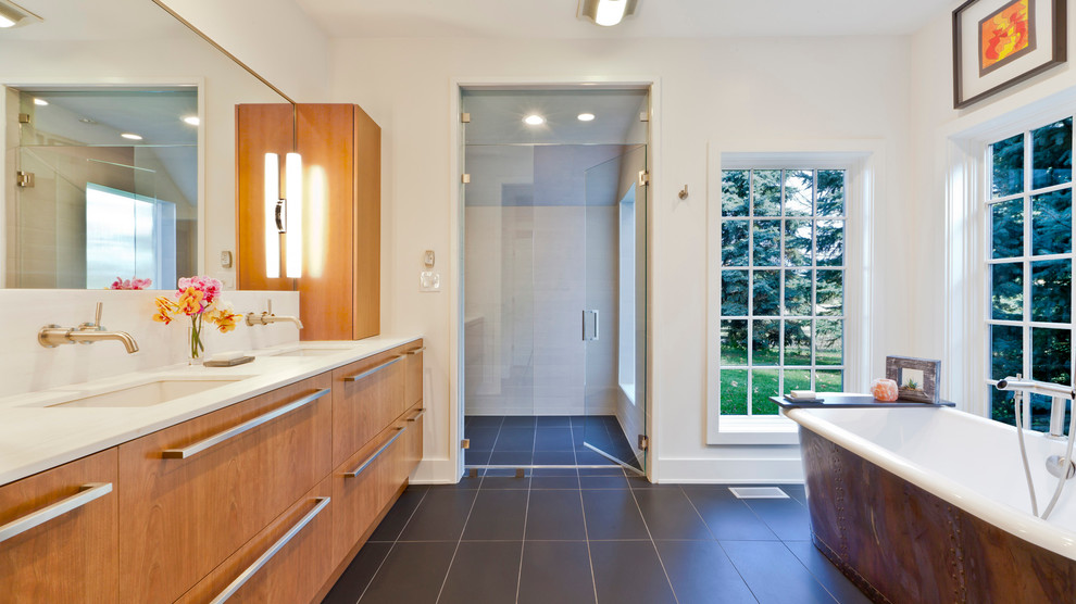 Cette photo montre une salle de bain principale tendance en bois brun de taille moyenne avec un placard à porte plane, une baignoire indépendante, une douche à l'italienne, un carrelage gris, des carreaux de porcelaine, un mur blanc, un sol en carrelage de porcelaine, un lavabo encastré et un plan de toilette en marbre.