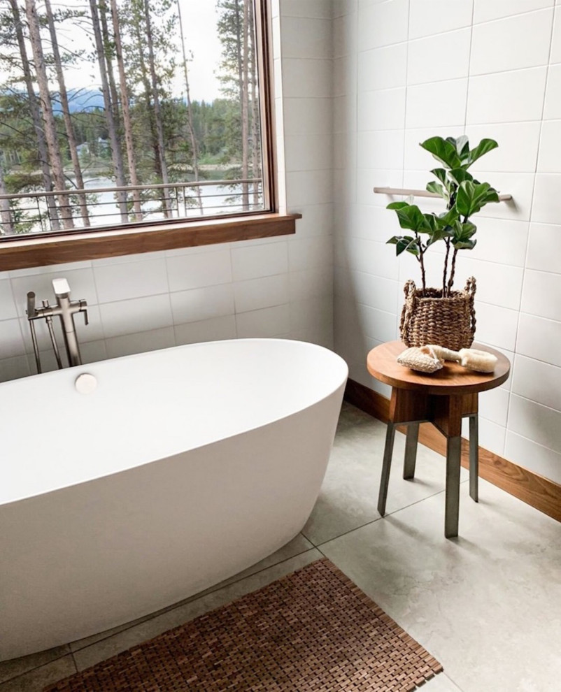 This is an example of a scandi bathroom in Denver with a freestanding bath, white tiles, ceramic tiles, white walls, porcelain flooring, grey floors and a wall niche.