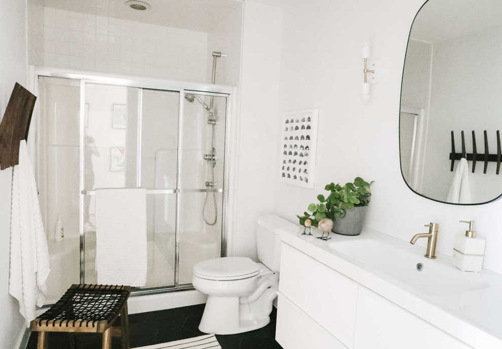 Photo of a medium sized scandi family bathroom in Other with flat-panel cabinets, white cabinets, a one-piece toilet, white walls, porcelain flooring, an integrated sink, black floors, a sliding door, white worktops, a single sink and a floating vanity unit.