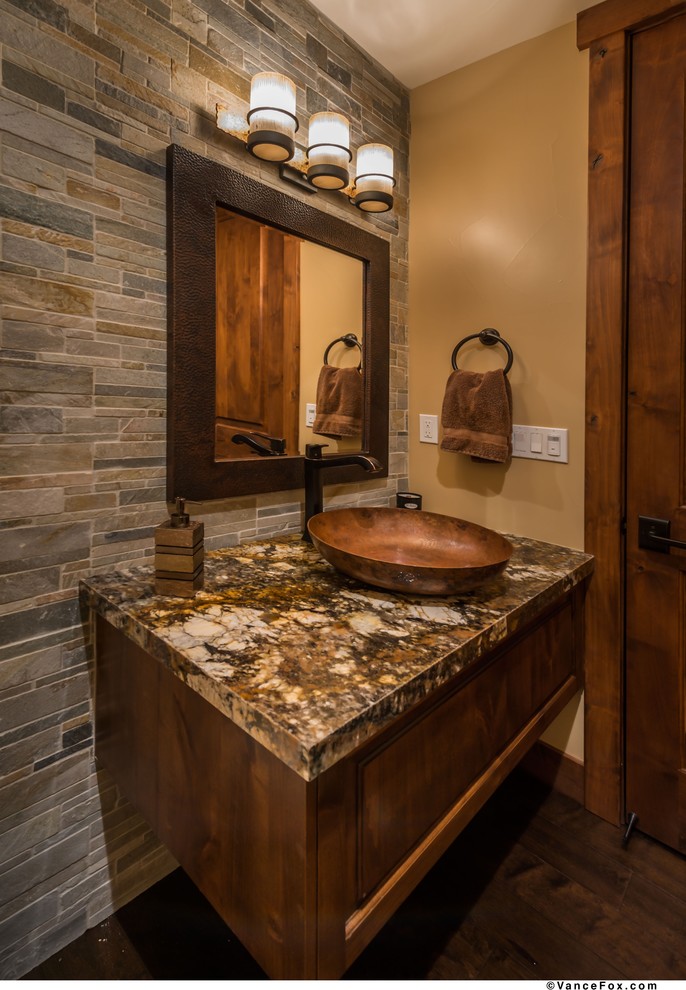 Modelo de cuarto de baño rústico de tamaño medio con armarios estilo shaker, puertas de armario de madera en tonos medios, paredes beige, suelo de madera oscura, aseo y ducha, lavabo sobreencimera y encimera de granito