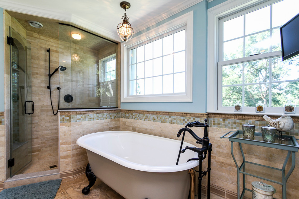 Immagine di una stanza da bagno padronale classica di medie dimensioni con vasca con piedi a zampa di leone, doccia aperta, piastrelle marroni, piastrelle in pietra, pavimento in travertino e pareti blu