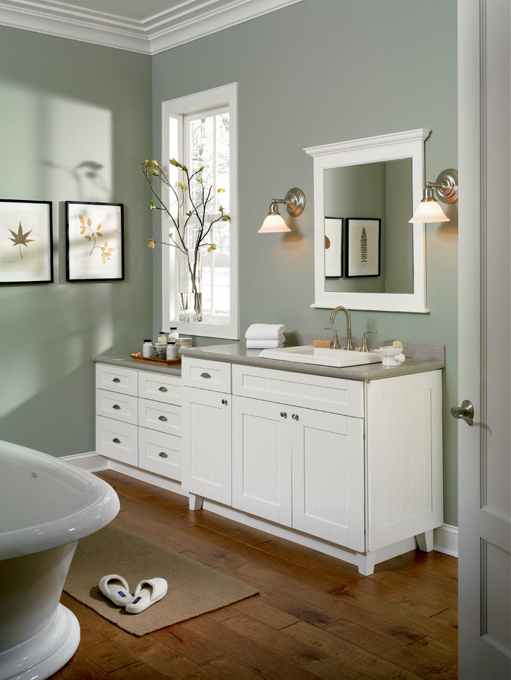 Klassisk inredning av ett mellanstort grå grått badrum med dusch, med luckor med lamellpanel, vita skåp, ett fristående badkar, gröna väggar, mörkt trägolv, ett nedsänkt handfat och brunt golv