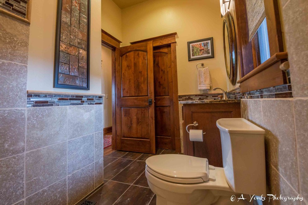 Cette image montre une salle d'eau chalet en bois brun de taille moyenne avec un placard à porte shaker, WC à poser, un carrelage beige, un carrelage marron, un carrelage gris, des carreaux de céramique, un mur jaune, un sol en ardoise, un lavabo encastré et un plan de toilette en granite.