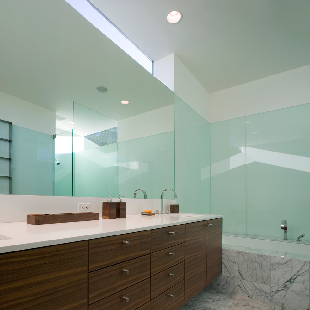 Foto de cuarto de baño moderno con lavabo bajoencimera, armarios con paneles lisos, puertas de armario de madera en tonos medios, bañera encastrada sin remate y baldosas y/o azulejos grises