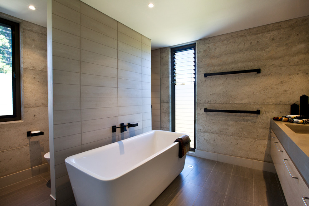 Foto de cuarto de baño actual con lavabo integrado, armarios con paneles lisos, bañera exenta y baldosas y/o azulejos de cemento