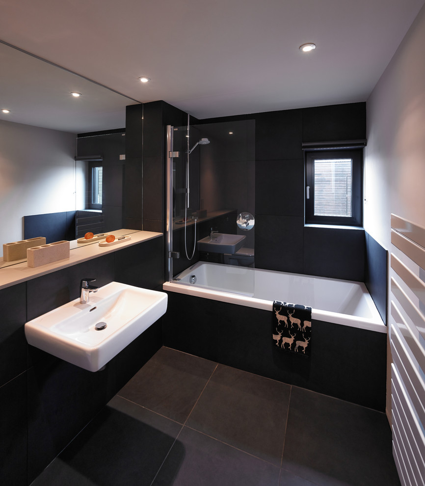 Réalisation d'une salle de bain design de taille moyenne avec un lavabo suspendu, une baignoire en alcôve, un combiné douche/baignoire, un carrelage noir et un mur noir.