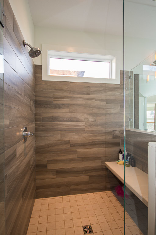 This is an example of a large contemporary ensuite bathroom in Vancouver with flat-panel cabinets, medium wood cabinets, a walk-in shower, white walls, porcelain flooring, a vessel sink, limestone worktops, beige floors, a hinged door and beige worktops.