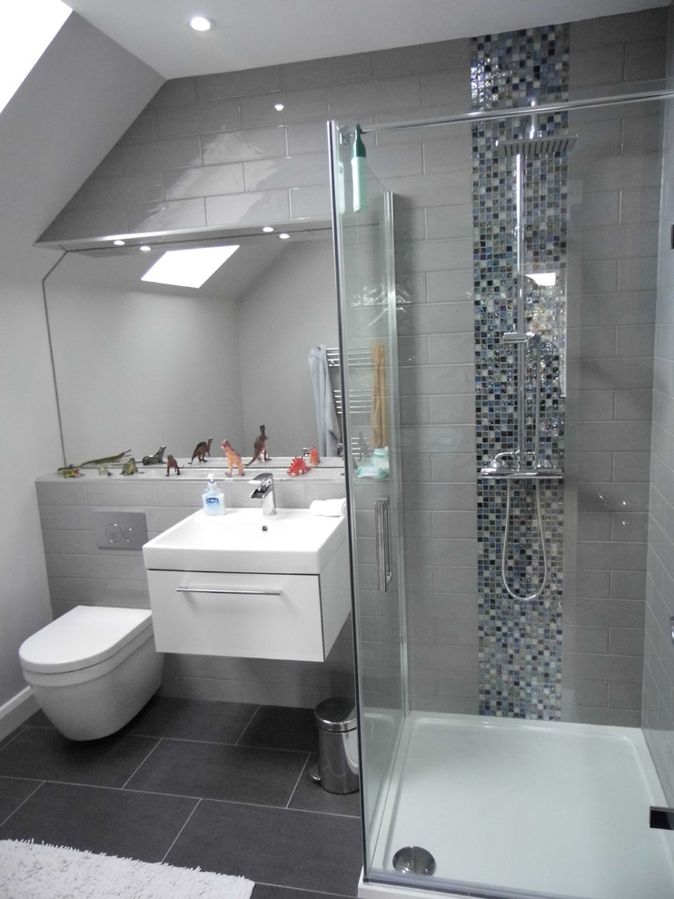 Foto de cuarto de baño infantil contemporáneo con ducha esquinera, sanitario de pared, baldosas y/o azulejos grises, paredes grises y suelo de baldosas de porcelana