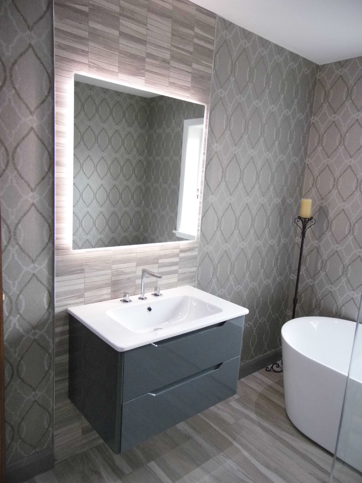 На фото: главная ванная комната в современном стиле с отдельно стоящей ванной, инсталляцией, серой плиткой, серыми стенами и светлым паркетным полом с