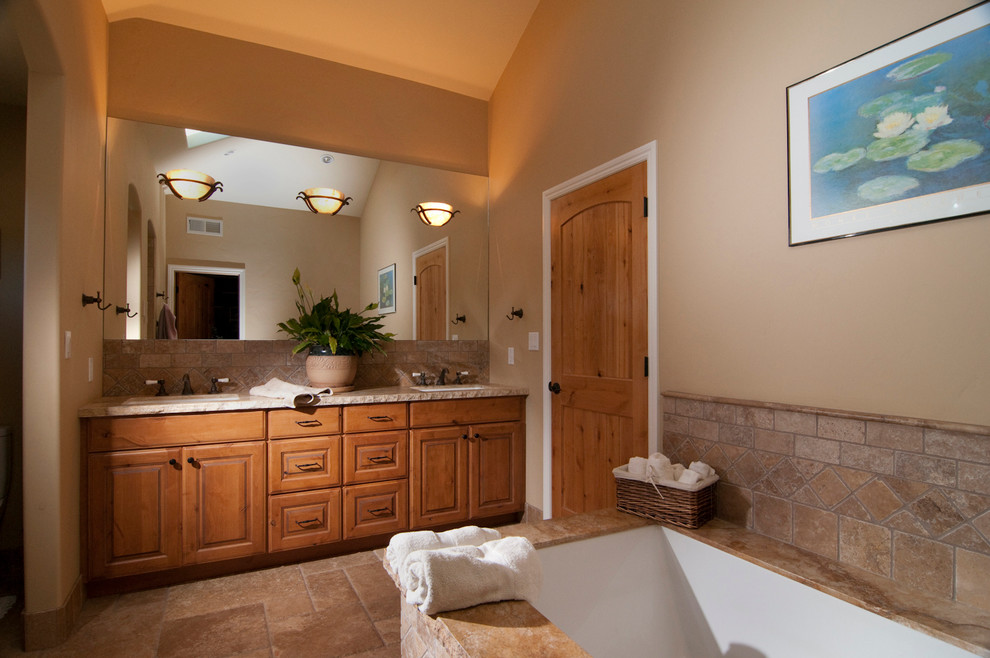 Foto di una stanza da bagno mediterranea con lavabo sottopiano, ante con bugna sagomata, ante in legno scuro, vasca sottopiano, doccia alcova, WC monopezzo, piastrelle marroni e piastrelle in pietra
