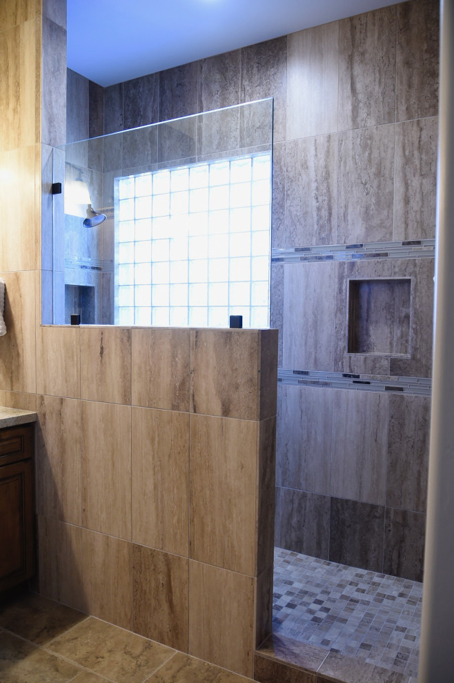 This is an example of a medium sized traditional ensuite bathroom in Phoenix with raised-panel cabinets, medium wood cabinets, beige tiles, stone tiles, grey walls, porcelain flooring, a submerged sink, granite worktops, brown floors, multi-coloured worktops, a shower bench, double sinks and a built in vanity unit.