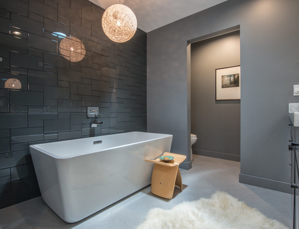 Design ideas for a medium sized contemporary ensuite bathroom in Phoenix with flat-panel cabinets, black cabinets, a freestanding bath, an alcove shower, a one-piece toilet, grey tiles, glass tiles, grey walls, ceramic flooring, a submerged sink and engineered stone worktops.
