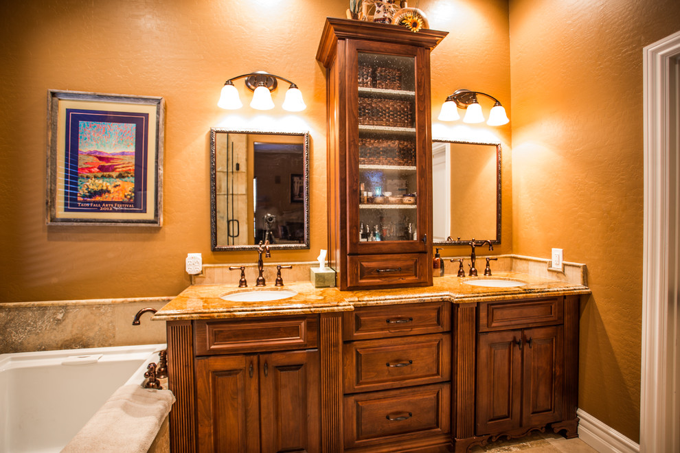 Esempio di una stanza da bagno padronale tradizionale di medie dimensioni con ante con bugna sagomata, ante in legno scuro, vasca sottopiano, pareti arancioni, lavabo sottopiano e top in granito