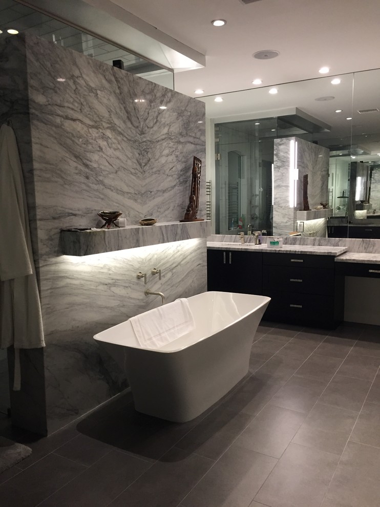 Modelo de cuarto de baño principal moderno grande con armarios con paneles lisos, puertas de armario de madera en tonos medios, bañera exenta, paredes blancas y lavabo bajoencimera