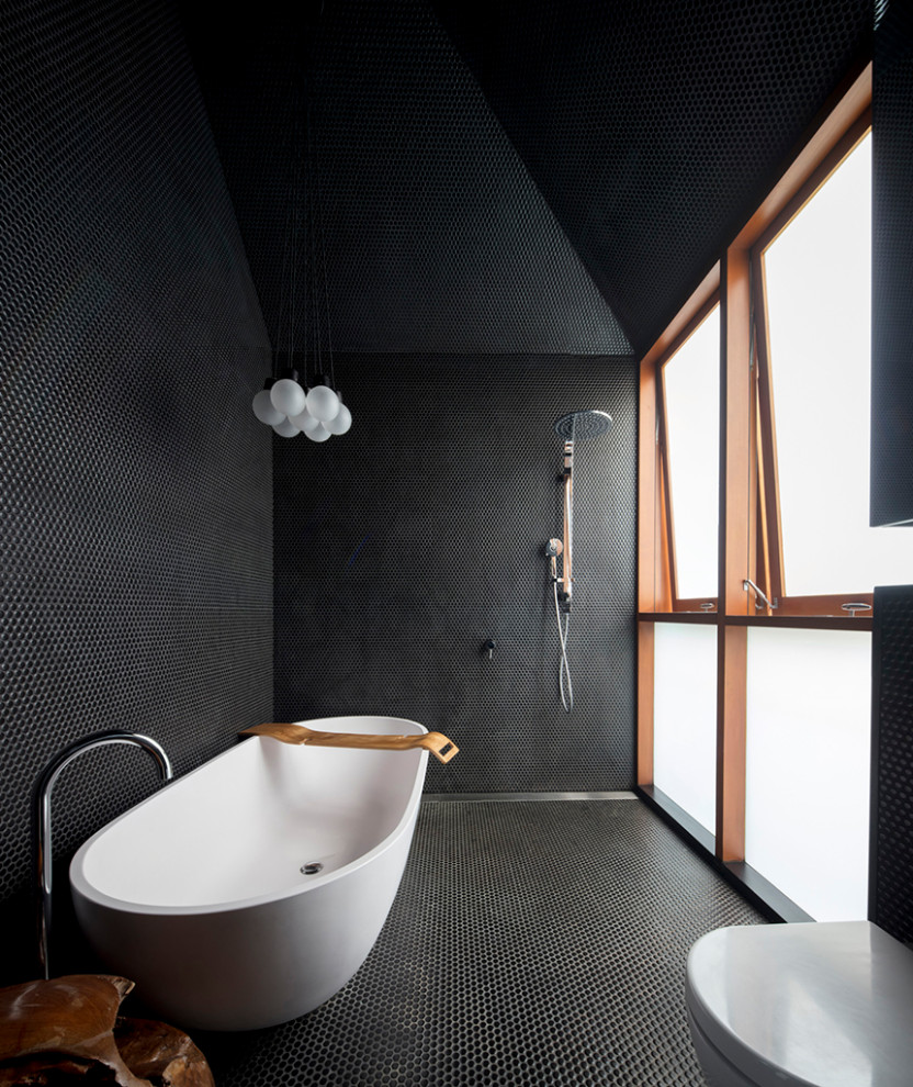 Immagine di una stanza da bagno con vasca freestanding, piastrelle nere, piastrelle a mosaico, pavimento nero e pavimento con piastrelle a mosaico
