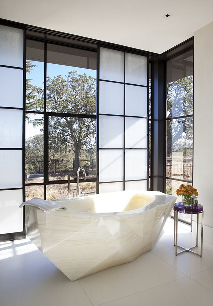 Cette image montre une grande salle de bain principale design avec une baignoire indépendante, un mur blanc, un sol en carrelage de porcelaine et un sol blanc.