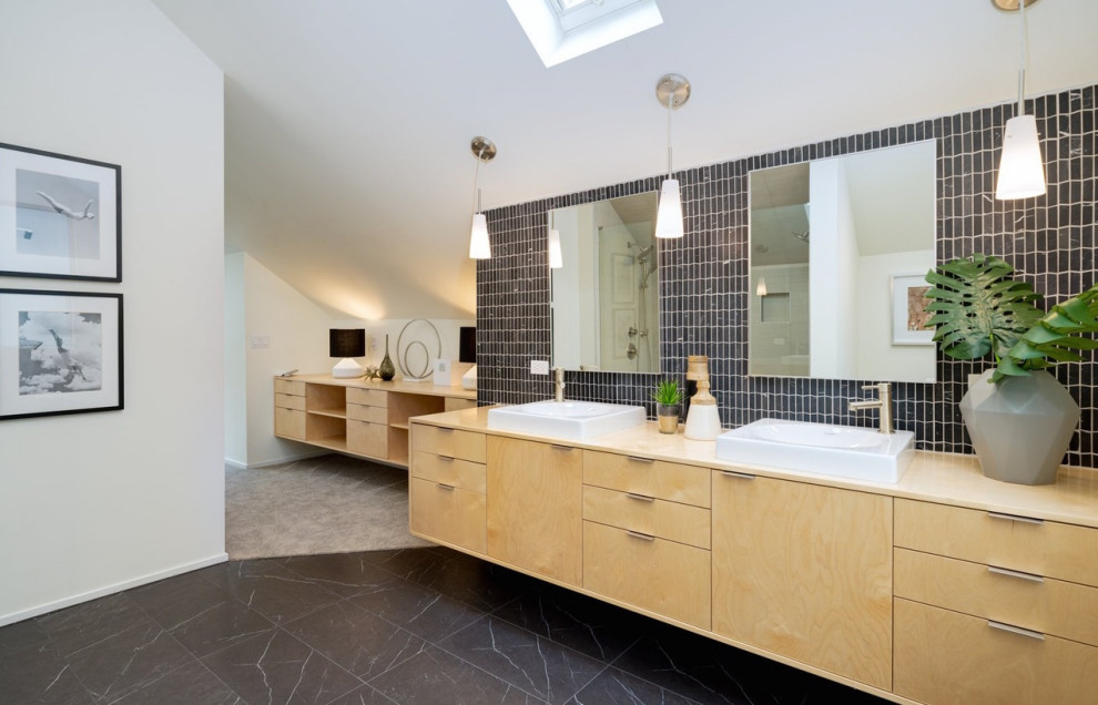 Пример оригинального дизайна: главная ванная комната в стиле ретро с плоскими фасадами, светлыми деревянными фасадами, черной плиткой, белыми стенами, настольной раковиной, черным полом, бежевой столешницей и зеркалом с подсветкой