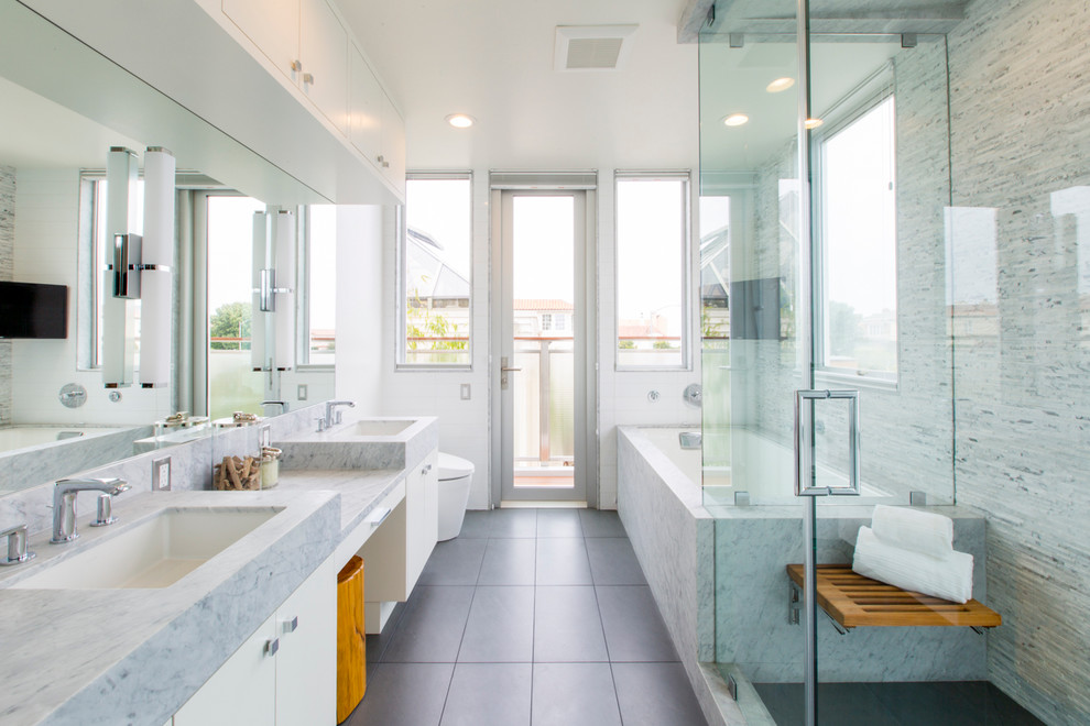 Cette image montre une salle de bain design avec un lavabo encastré, un placard à porte plane, des portes de placard blanches, une baignoire encastrée, une douche d'angle, un carrelage blanc et un mur blanc.
