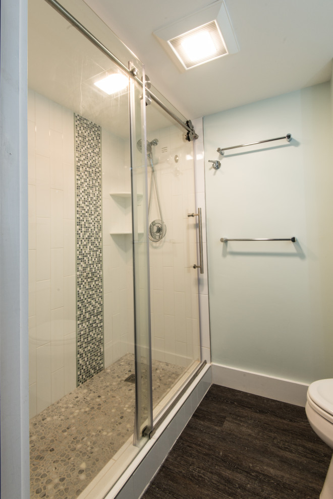 Bild på ett mellanstort funkis badrum med dusch, med en dusch i en alkov, en toalettstol med separat cisternkåpa, vit kakel, mosaikgolv och dusch med skjutdörr
