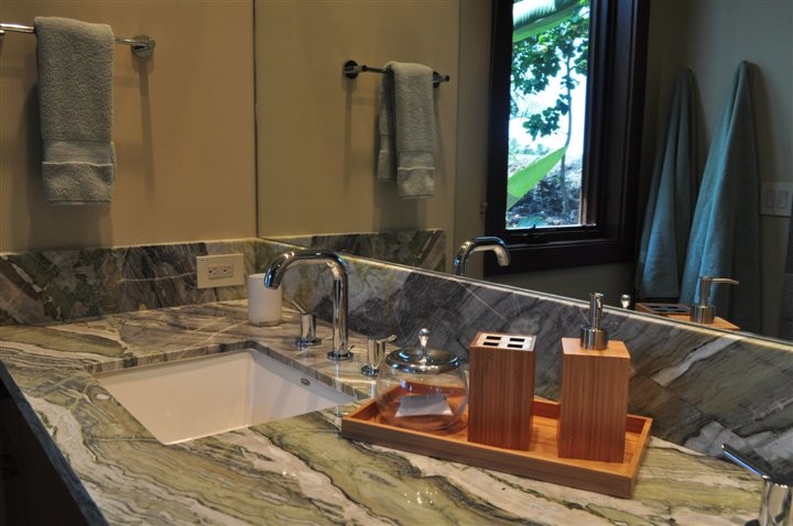 Exemple d'une grande salle de bain exotique avec des portes de placard marrons, un lavabo encastré, un plan de toilette en quartz et un plan de toilette vert.