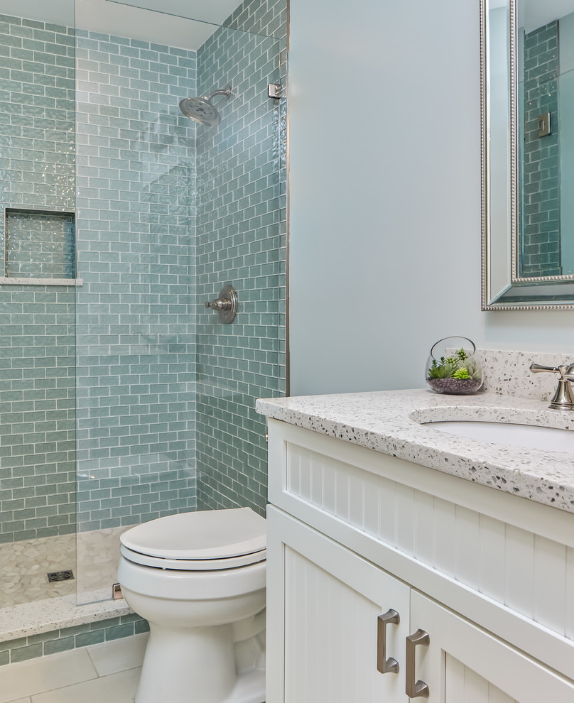 チャールストンにある高級な中くらいなビーチスタイルのおしゃれなバスルーム (浴槽なし) (シェーカースタイル扉のキャビネット、白いキャビネット、オープン型シャワー、一体型トイレ	、青いタイル、ガラスタイル、青い壁、磁器タイルの床、アンダーカウンター洗面器、再生グラスカウンター、白い床、オープンシャワー) の写真