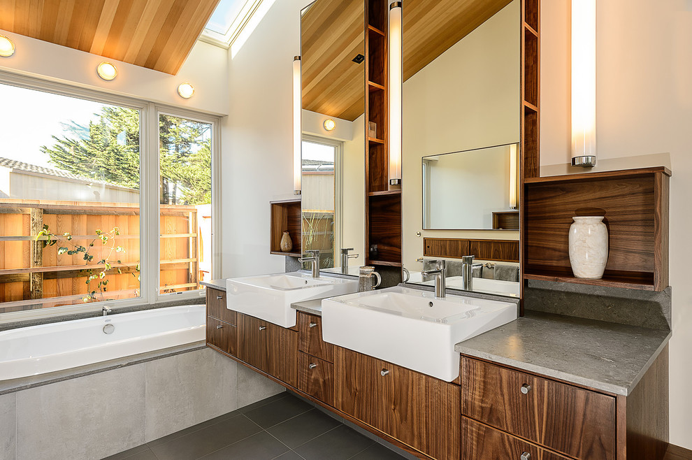 Photo of a midcentury bathroom in San Francisco with a vessel sink, flat-panel cabinets, dark wood cabinets, a built-in bath, grey tiles and grey worktops.