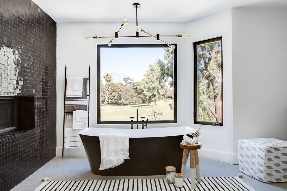 Modelo de cuarto de baño actual con bañera exenta, baldosas y/o azulejos negros, paredes blancas y suelo gris
