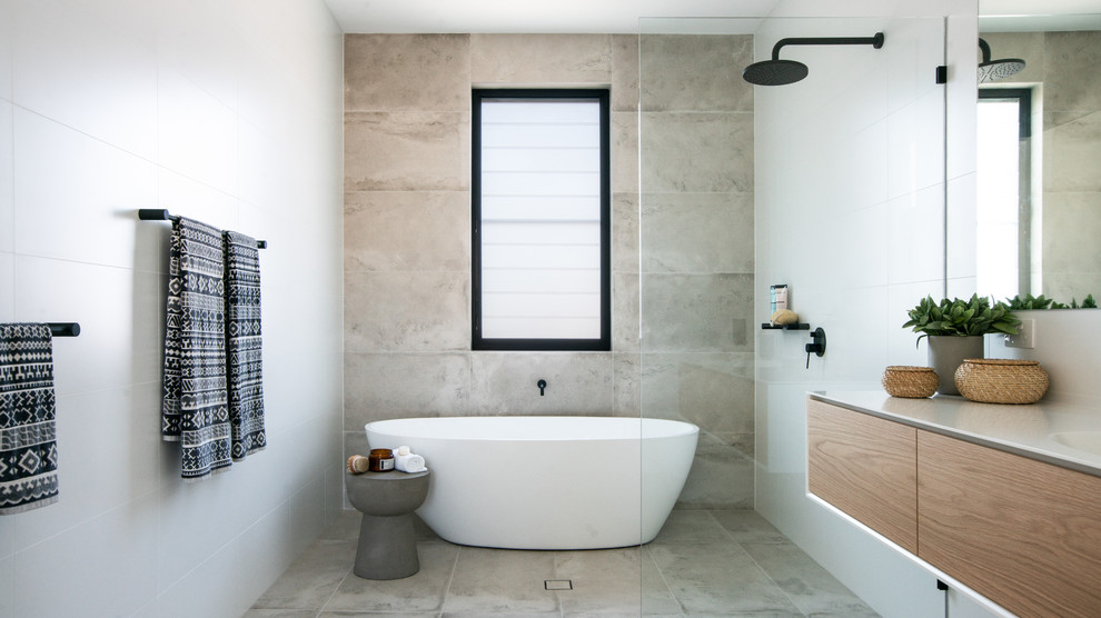 This is an example of a contemporary bathroom in Other with medium wood cabinets, a freestanding bath, ceramic tiles, white worktops, flat-panel cabinets, a built-in shower, grey tiles, white tiles, white walls, an integrated sink, grey floors and an open shower.