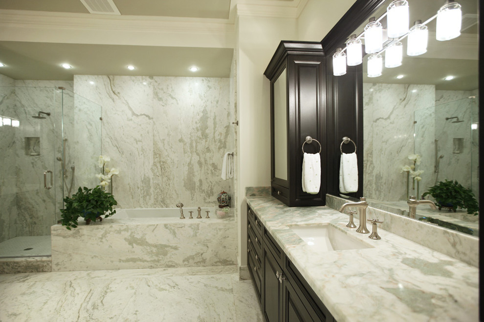 Cette image montre une salle de bain traditionnelle avec un lavabo encastré, des portes de placard noires, un plan de toilette en marbre, une baignoire d'angle, une douche ouverte, un carrelage blanc, des dalles de pierre, un mur blanc et un sol en marbre.