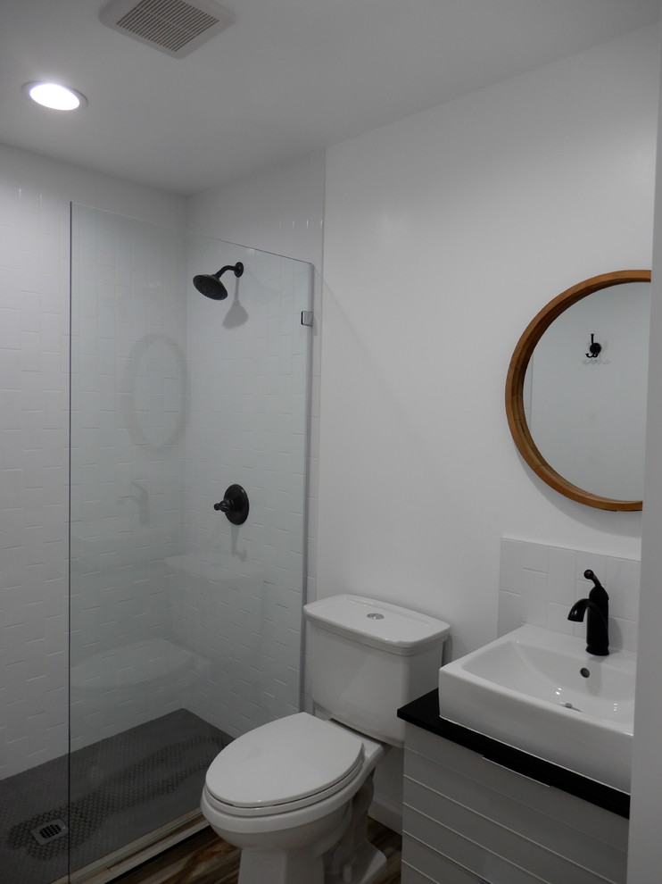 Idéer för ett litet modernt svart badrum med dusch, med luckor med glaspanel, vita skåp, en öppen dusch, en toalettstol med separat cisternkåpa, vit kakel, keramikplattor, vita väggar, klinkergolv i porslin, ett fristående handfat, laminatbänkskiva, brunt golv och med dusch som är öppen