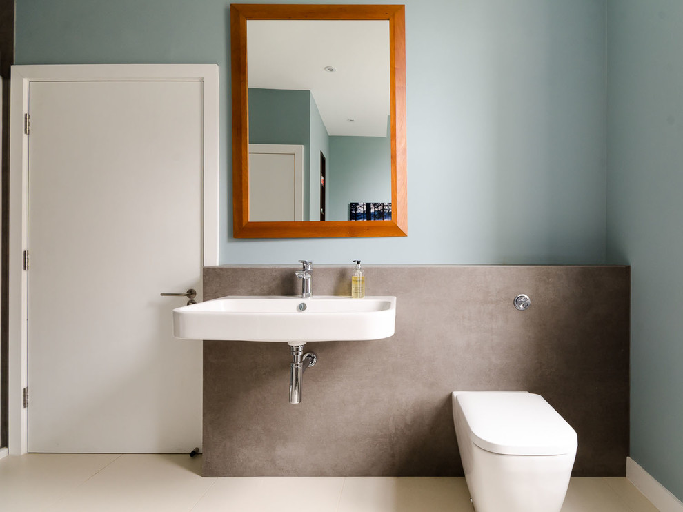 Exemple d'une salle de bain tendance avec un lavabo suspendu et un mur bleu.