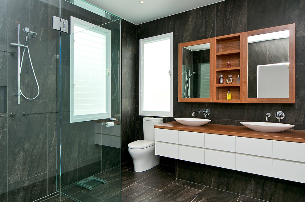 Photo of a large modern ensuite bathroom in Brisbane with a vessel sink, wooden worktops, grey tiles, multi-coloured walls, flat-panel cabinets and white cabinets.