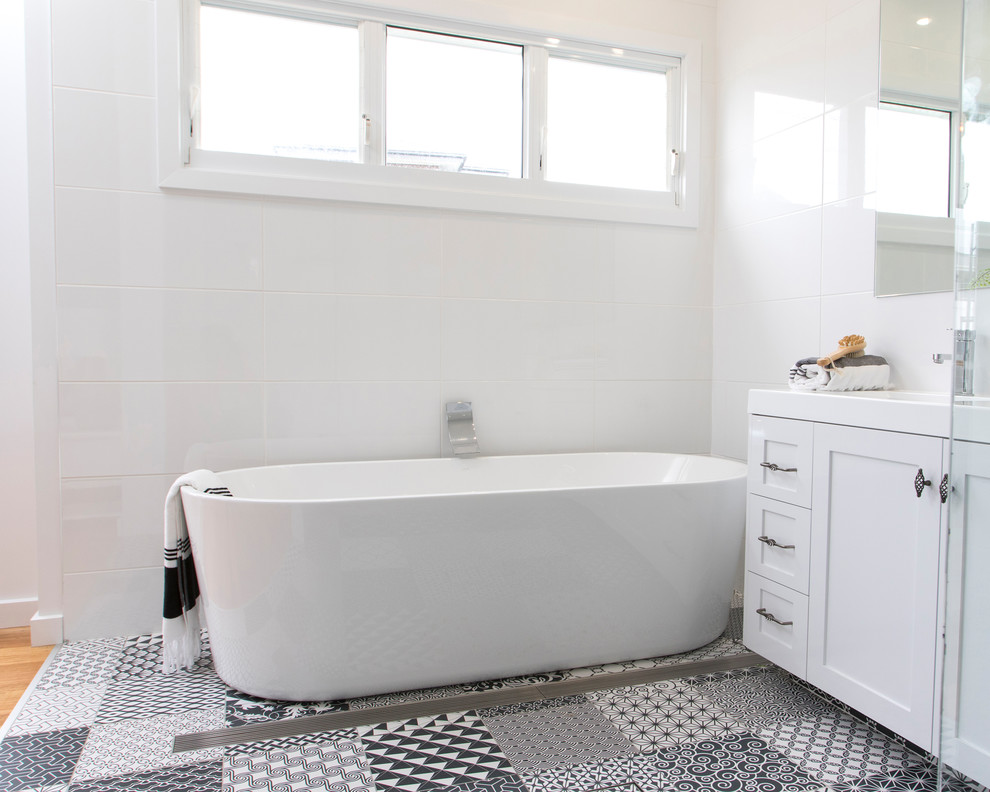 Пример оригинального дизайна: главная ванная комната среднего размера в морском стиле с фасадами в стиле шейкер, белыми фасадами, отдельно стоящей ванной, угловым душем, белой плиткой, керамической плиткой, полом из керамической плитки, монолитной раковиной и душем с распашными дверями