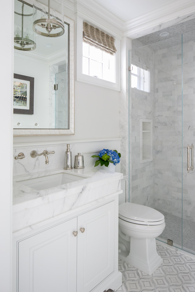 Coastal bathroom in Orange County with beaded cabinets, white cabinets, an alcove shower, white tiles, grey walls, a submerged sink, white floors, a hinged door, white worktops, a wall niche, a single sink, a built in vanity unit and wainscoting.