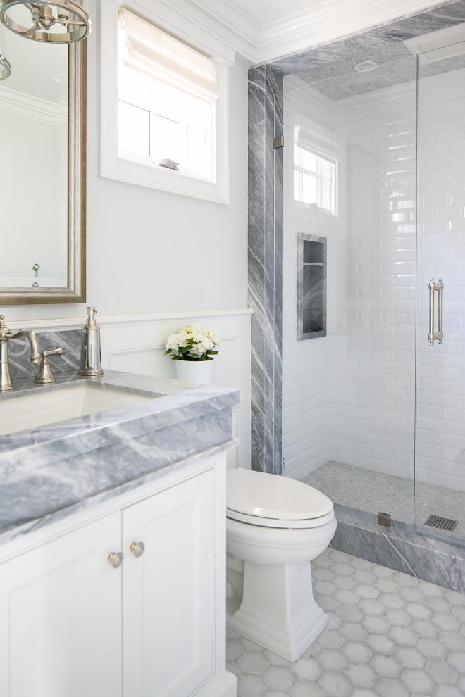 Foto på ett maritimt grå badrum, med luckor med profilerade fronter, vita skåp, en dusch i en alkov, vita väggar, ett undermonterad handfat, vitt golv och dusch med gångjärnsdörr