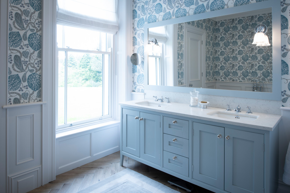 Idée de décoration pour une salle de bain principale tradition avec un placard à porte shaker, des portes de placard bleues, une baignoire indépendante, un lavabo intégré et un plan de toilette en marbre.