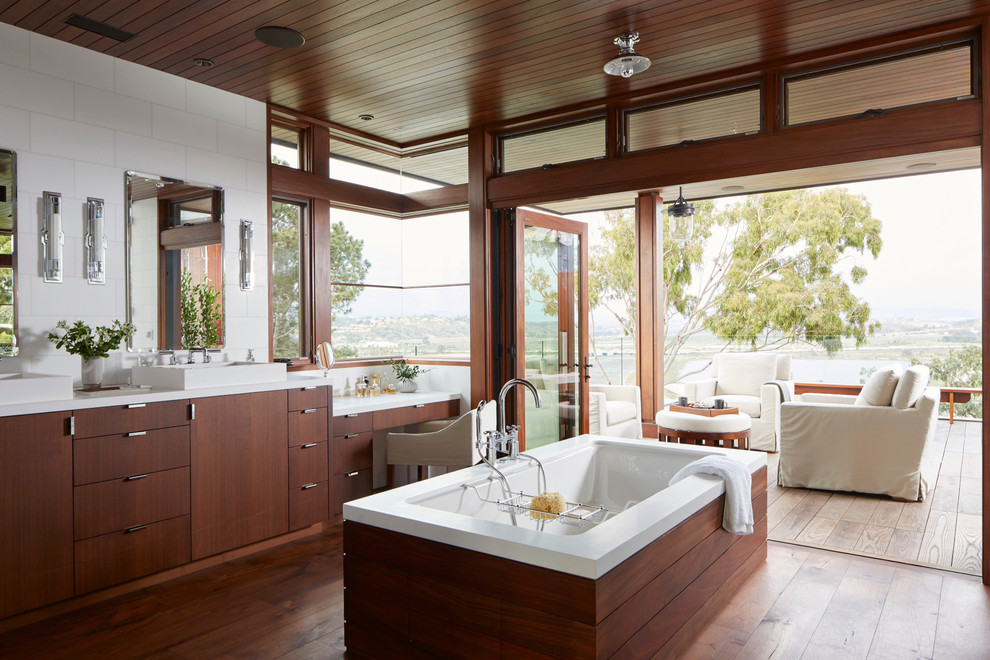 Exempel på ett modernt en-suite badrum, med släta luckor, skåp i mellenmörkt trä, ett undermonterat badkar, vit kakel, mellanmörkt trägolv och ett fristående handfat