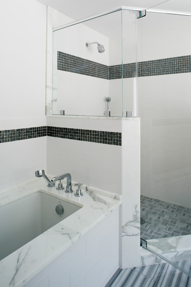 Klassisk inredning av ett stort en-suite badrum, med släta luckor, vita skåp, ett undermonterat badkar, en hörndusch, grå kakel, vit kakel, glaskakel, vita väggar, laminatgolv, ett undermonterad handfat, marmorbänkskiva, grått golv och dusch med gångjärnsdörr